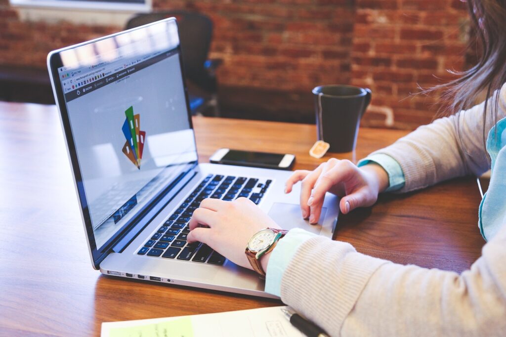 Person using a laptop to research AI tools for small businesses. Text on screen includes "cost-effective solutions" and "increased efficiency," highlighting key benefits of implementing AI.